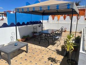 a table and chairs under an umbrella on a patio at Riad Aicha in Asilah