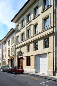 a building with two cars parked in front of it at Hotel Hine Adon Fribourg in Fribourg