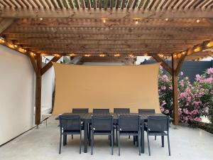 a table and chairs under a wooden pergola at Gite pour 8 p avec Piscine sur domaine 3Ha in Béziers