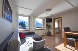 ein Wohnzimmer mit einem Sofa, einem Tisch und Fenstern in der Unterkunft Seegärtli Riverside Apartment in Goldswil