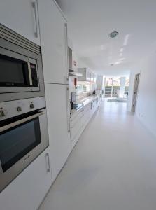 Una cocina blanca con suelos y electrodomésticos blancos. en White Beach Villa, en Sagres