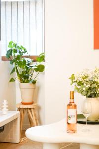 a bottle of wine sitting on a table with plants at Le Cocon d'Alice - Cosy, calme, central et climatisé in Annecy