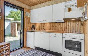 a kitchen with white cabinets and a stove at Three-Bedroom Holiday Home In Follenslev in Føllenslev +16 photos