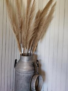 a metal vase with feathers in it next to a wall at Alquiler de casa temporario en Suipacha "Lo de Juancho" in Suipacha