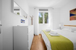 a white bedroom with a bed with a yellow blanket at House , Seafront Apartment Pelegrin in Stomorska
