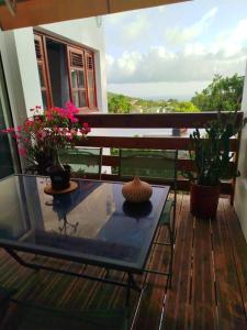 a glass table on a balcony with flowers on it at Petit cocon vue mer in Gourbeyre
