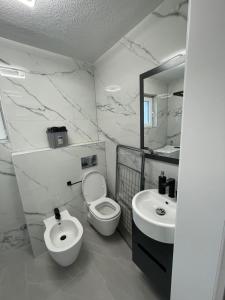 a white bathroom with a toilet and a sink at Una deluxe home ELLA in Bihać