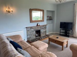 Una sala de estar con un sofá y una chimenea. en Cockles Farm Bungalow, en Saltash