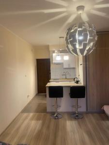 a kitchen with two bar stools and a large light fixture at Studio Gdańsk Śródmieście in Gdańsk