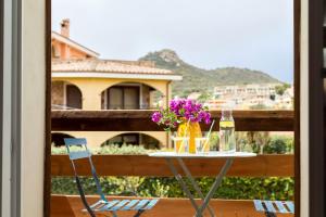 a table with flowers and a bottle of wine on a balcony at Apartment seahorse in Villasimius