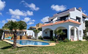a villa with a swimming pool in front of a house at Villa Casa Deraoui in Tangier