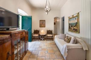 a living room with a couch and a flat screen tv at The Old One by All About Paxos in Kourtaíïka