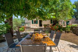 a wooden table and chairs in a yard at The Old One by All About Paxos in Kourtaíïka