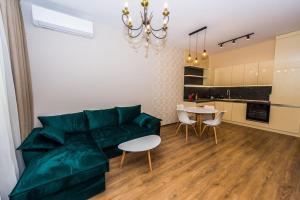 a living room with a green couch and a table at Flora Apartment in Burgas City