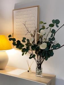a vase of flowers on a table next to a lamp at KALUKA Málaga center apartment - free parking in Málaga