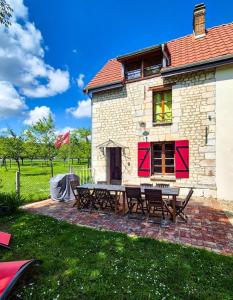 a brick building with picnic tables in front of it at Maison normande au bord de Seine, Le Verger de Pacôme in Anneville-Ambourville