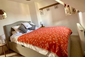 een slaapkamer met een bed met een rood dekbed bij Holly Cottage in Cirencester +10 foto's