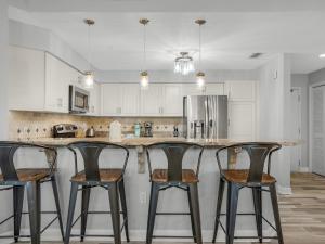 a kitchen with a counter with four bar stools at Blue Mountain Beach Condominium 102 by Newman-Dailey in Santa Rosa Beach +27 photos