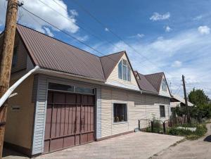 a house with a brown roof and a garage at Olzho Hostel in Karakol