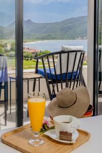 a hat and a glass of orange juice on a table at Hotel AQUILO in Petrovac na Moru