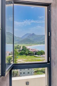 a window with a view of the water and mountains at Hotel AQUILO in Petrovac na Moru