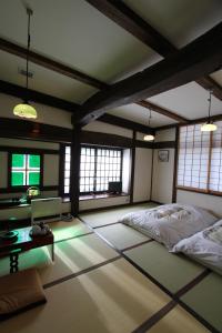 a room with a bed and a table and windows at Minshuku Takizawa in Takayama