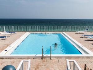 a person in a swimming pool with the ocean in the background at Gulfside 503 in Fort Walton Beach