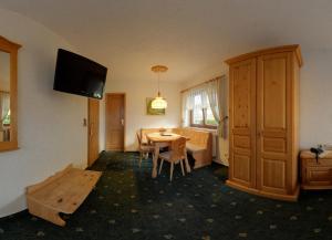 Hotel Alpenhof في Markneukirchen: غرفة معيشة مع طاولة وتلفزيون على الحائط