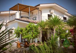 a white house with a balcony and palm trees at vila SEJUDA Alberghetto in Peschici