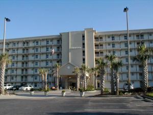 a large hotel with palm trees in a parking lot at Island Echos 3L in Fort Walton Beach