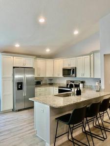 a kitchen with white cabinets and a kitchen island with chairs at Brand New, Peaceful, and Dogs Stay Free in Marion Oaks