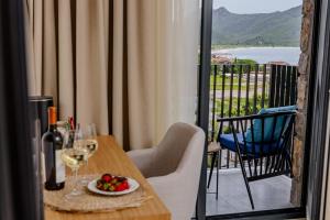 a table with a plate of fruit and wine glasses on a balcony at Hotel AQUILO in Petrovac na Moru