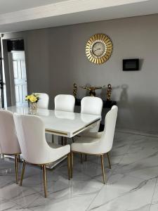 a dining room with a white table and white chairs at Percyville in Polokwane