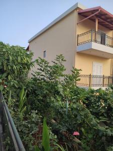a building with a balcony and some bushes at Villa Janilla in Dhërmi