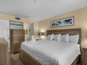 a bedroom with a large white bed and a dresser at Crystal Sands 103A by Newman-Dailey in Destin