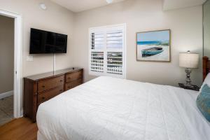 a bedroom with a white bed and a television at Waters Edge 507 in Fort Walton Beach +49 photos