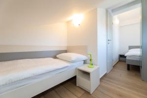 a small white bedroom with a bed and a table at Apartments Crnekovic IX in Baška