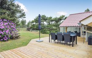 a wooden deck with a table and chairs on it at Awesome Home In Blåvand With Wifi in Blåvand