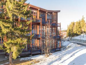 duży drewniany budynek z śniegiem przed nim w obiekcie Duplex rénové calme 6/7 pers. avec balcon - FR-1-346-332 w mieście Arc 1800