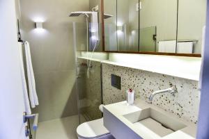 a bathroom with a sink and a toilet and a mirror at Casa João de Barro - Praia de Guaecá in Barequeçaba