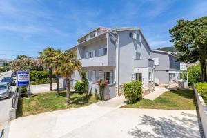 a white house with palm trees and a street at Apartments Crnekovic IX in Baška
