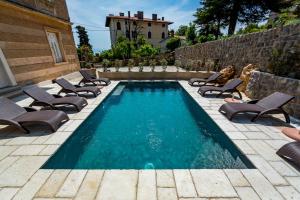 a swimming pool with chaise lounges and chairs around it at Apartment Bozic in Lovran