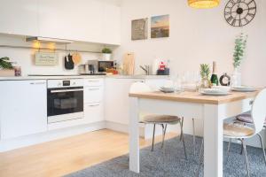 a white kitchen with a table and chairs at Apartment Meerblick-Balkon-Strand-Golf-TV-Stilvoll in Eckernförde