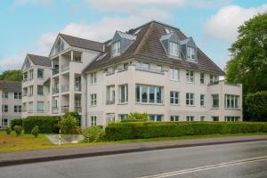 a large white building with a brown roof at Apartment Meerblick-Balkon-Strand-Golf-TV-Stilvoll in Eckernförde