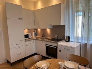 kuchnia z białymi szafkami i stołem z krzesłami w obiekcie Book-A-Room Salzburg Apartment 33 w mieście Salzburg