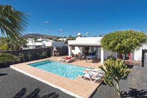 una piscina con sillas y una casa en Villa Flamingo by Villa Plus, en Playa Blanca