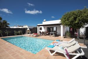 Una piscina con tumbonas y una casa. en Villa Flamingo by Villa Plus, en Playa Blanca