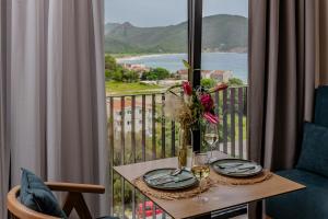 a table with wine glasses and flowers on a balcony at Hotel AQUILO in Petrovac na Moru