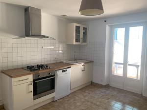 a kitchen with white cabinets and a stove top oven at Gîte La Dame du Lac in Paimpont