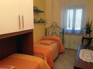 - une chambre avec 2 lits avec des draps orange et une fenêtre dans l'établissement Il Baglivo, à Agnone